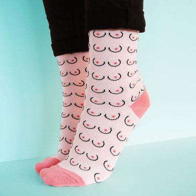 Person's feet wearing pink boob printed socks Nudie Co