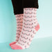 Person's feet wearing pink boob printed socks Nudie Co