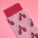 Close up of pink cotton socks with a clitoris print over a pink background Nudie Co