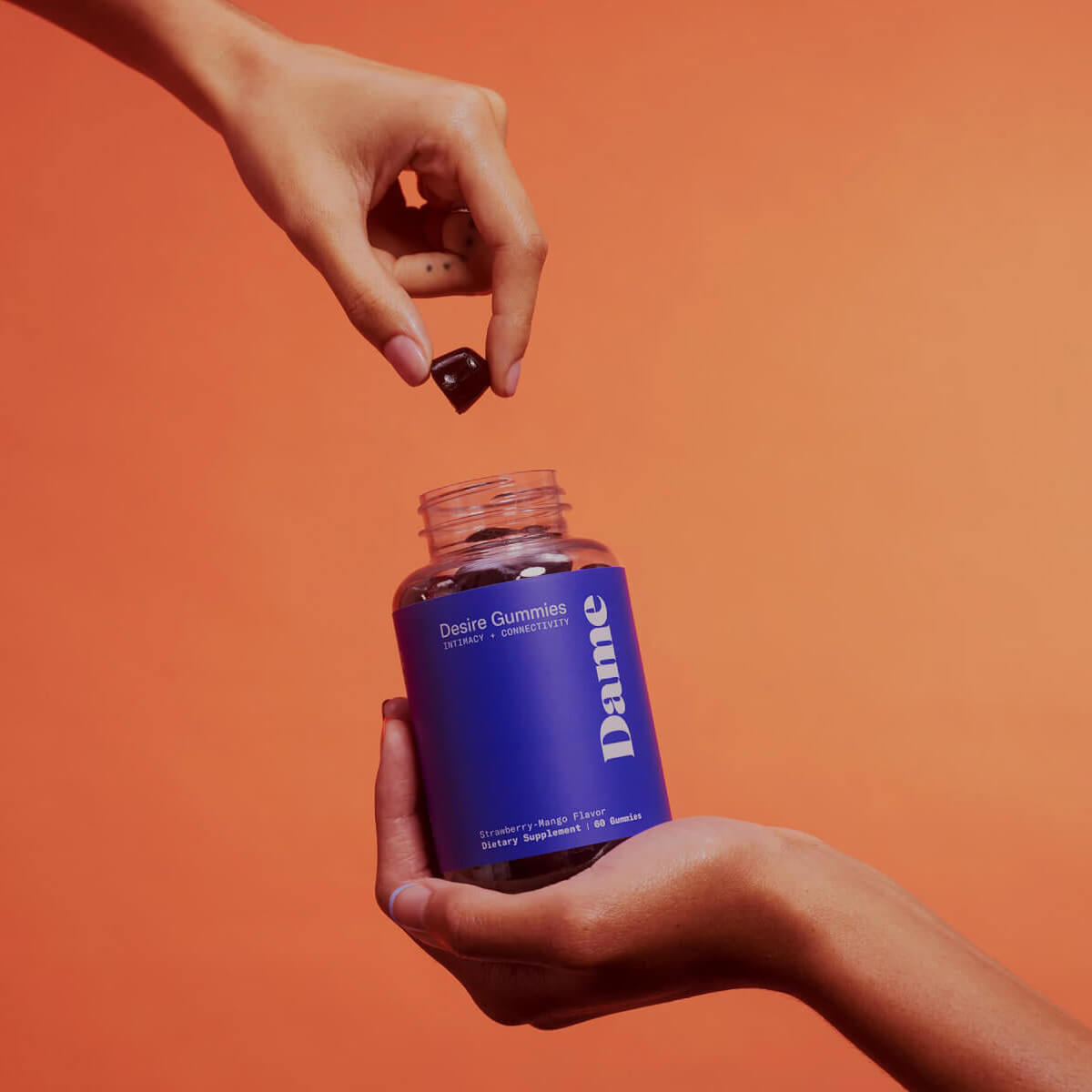 Hand holding a jar of gummies for sexual desire while other hand gets one out of the jar Nudie Co