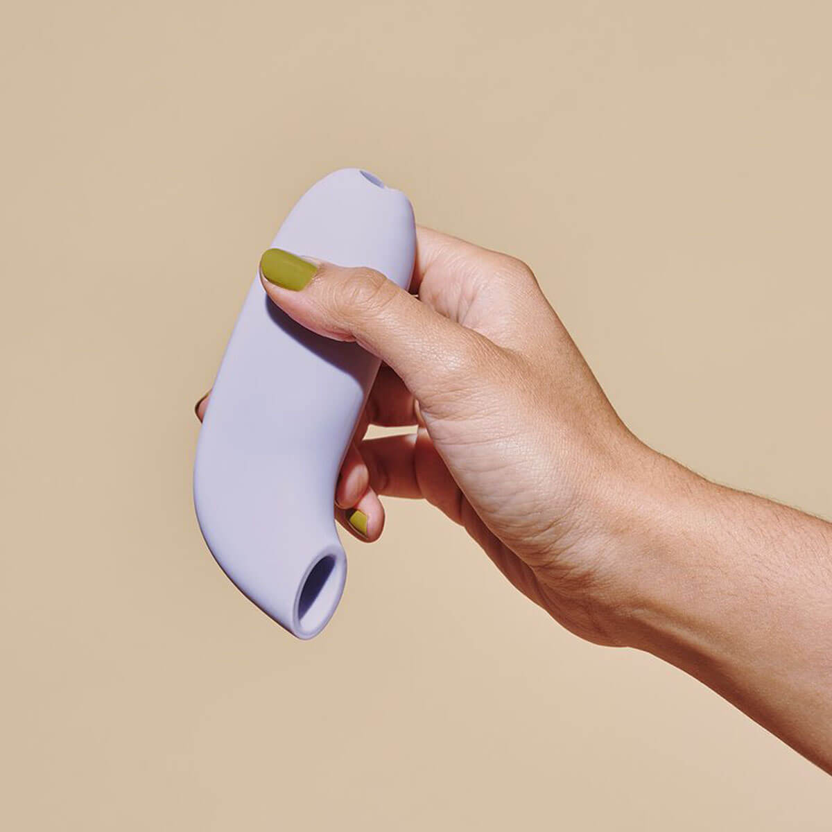 Hand with green nail polish holding a lilac silicone suction vibrator with a wide mouth for clitoral stimulation Nudie Co
