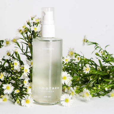 Bottle of Momotaro Apotheca Hydrosol organic toner amongst small white flowers Nudie Co