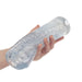 Hand holding a Cyclone Dual Ribbed Stroker XL in clear TPE on white background Nudie Co