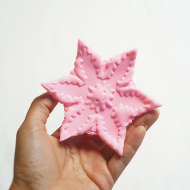 Hand holding a pink star-shaped silicone vibrator for all genders Nudie Co