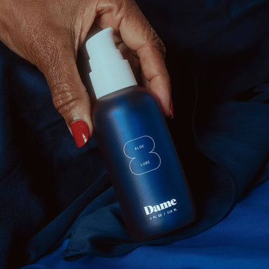 Hand holding a blue bottle of aloe vera intimate lubricant Nudie Co