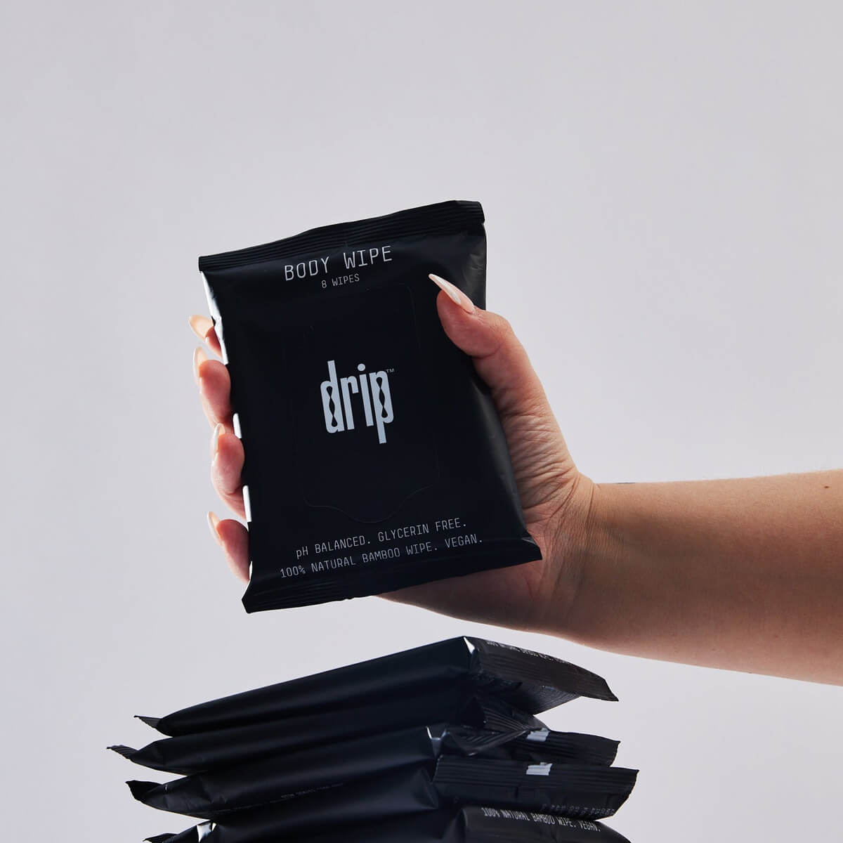 Hand holding a Black packet of 8 Drip body wipes for intimate care Nudie Co