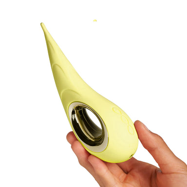 Hand holding a yellow teardrop-shaped silicone clitoral vibrator with a metallic ring on a white background Nudie Co