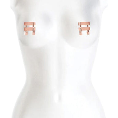 Rose gold metal nipple clamps with two adjustable bars with screws placed on white mannequin Nudie Co
