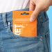 Close=up of hand placing a Tenga Pocket orange packaging inside their jeans' pocket Nudie Co