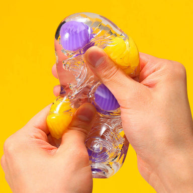 Someone squishing and twisting a gel masturbation sleeve with textured purple and yellow marbles inside Nudie Co