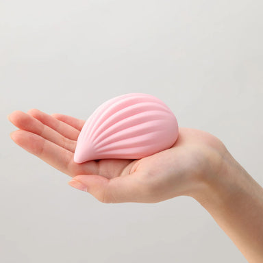 Woman's hamd holding a pink Kushi waterdrop-shaped ribbed clitoral vibrator by Tenga Iroha+ Nudie Co