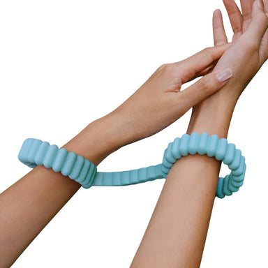Two hands wearing turquoise silicone cuffs on a white background Nudie Co