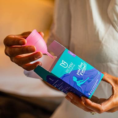 Woman holding a pink silicone and latex-free menstrual cup Nudie Co