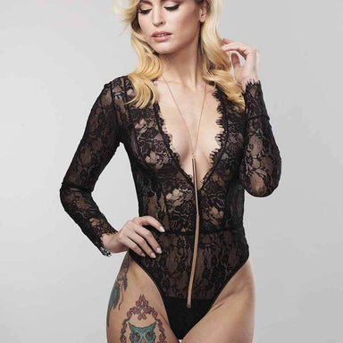 Woman wearing a black lace bodysuit and a long gold metal necklace with sets of chains at the end Nudie Co