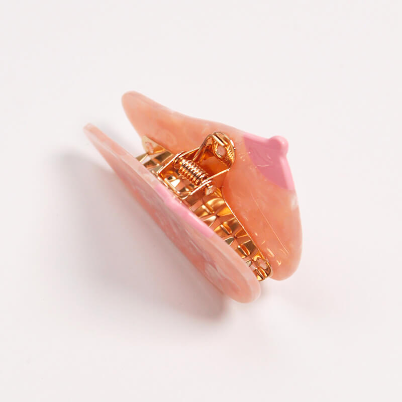 View of the golden clip inside of a breast-shaped hair clip Nudie Co