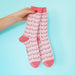 Woman's hand holding two pink socks with boob print Nudie Co