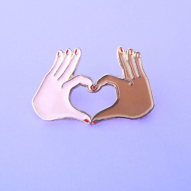 Enamel pin with two hands forming a love heart Nudie Co