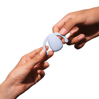 Two people holding a purple silicone vibrator for clitoris with two wings on the side to nest inside labia  Nudie Co