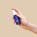Hand holding a small blue bottle of natural arousal serum with white pump Nudie Co
