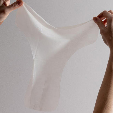Image of a woman holding up an unfolded Fig Femme Restore vulva sheet mask for intimate care Nudie Co