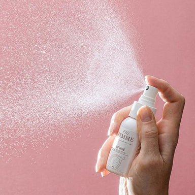 Woman's hand spraying a bottle of Fig Femme Revive Hydrating Mist for delicate intimate care Nudie Co