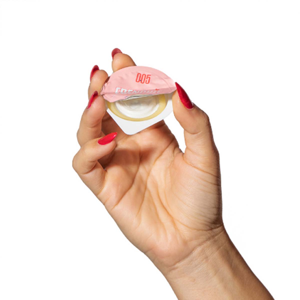 Woman'd hand with red nails, holding a single packaging of a Frenchie Vegan condom Nudie Co