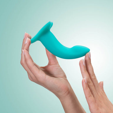 Woman bending a small green silicone dildo in her hands over a green background Nudie Co