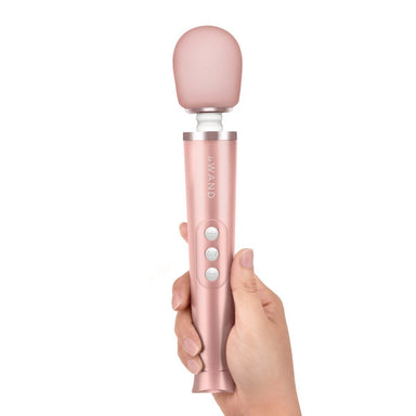 Woman's hand holding up a Rose gold Le Wand cordless rechargeable massager with soft silicone head Nudie Co