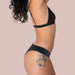 Side view of woman wearing black bra and black bikini latex underwear Nudie Co