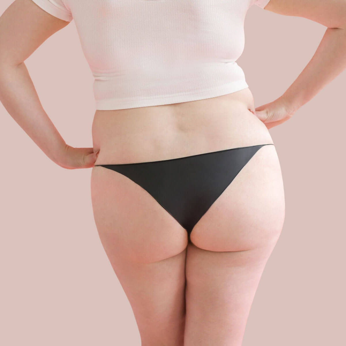 Rear view of woman wearing black bra and black bikini latex underwear Nudie Co