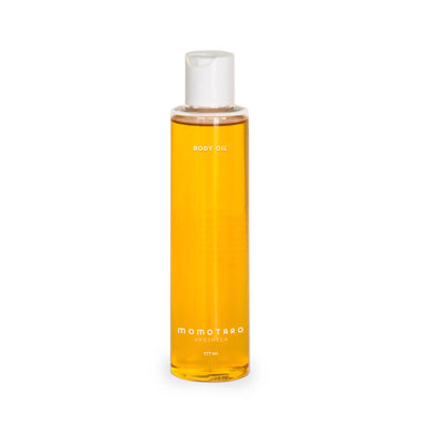 Tall bottle of yellow-coloured body oil with white cap Nudie Co