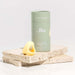 Small yellow finger vibrator besides its green circular packaging on top of two slabs of granite Nudie Co