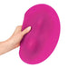 Female's hand holding a pink circular silicone vibrating pad with twi ridges for grinding Nudie Co