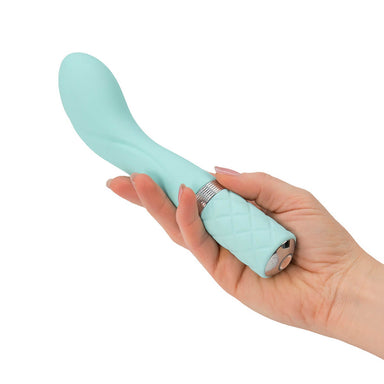Hand holding a teal G-spot vibrator with curved tip and padded handle Nudie Co