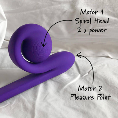 Purple silicone vibrator with two stimulation heads on white sheet Nudie Co