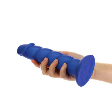 Hand holding a large silicone dildo with ribbed texture Nudie Co