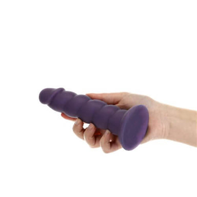 Hand holding a purple girthy silicone dildo with ridges on the shaft and a suction cup at the bottom Nudie Co