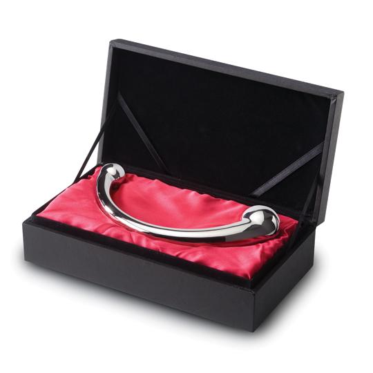 Side view of a curvded stainless steel pleasure wand  with two balls on either side sitting in a black box lined with red satin Nudie Co